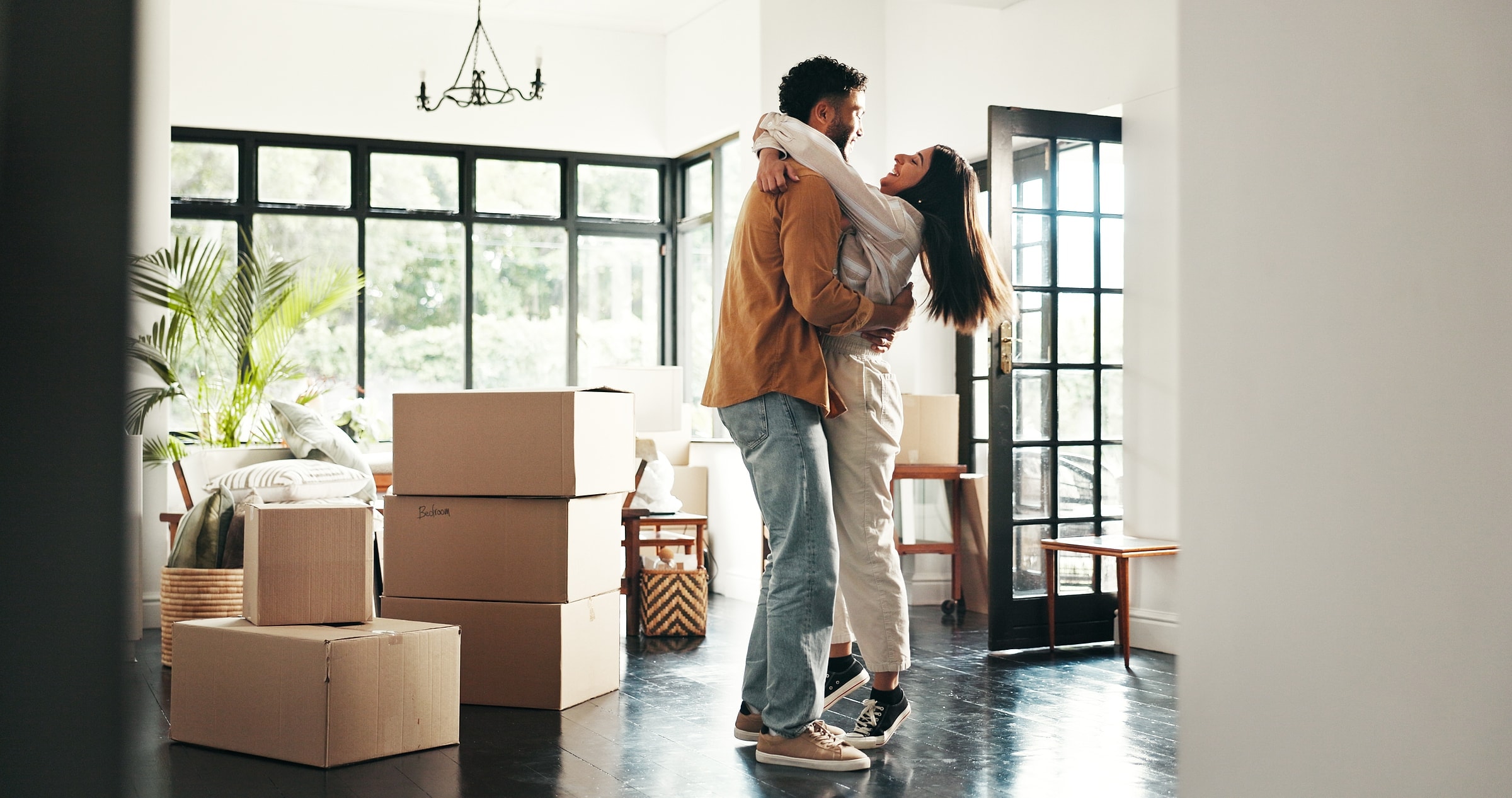 Un couple s’enlace au milieu des cartons, dans un appartement lumineux.